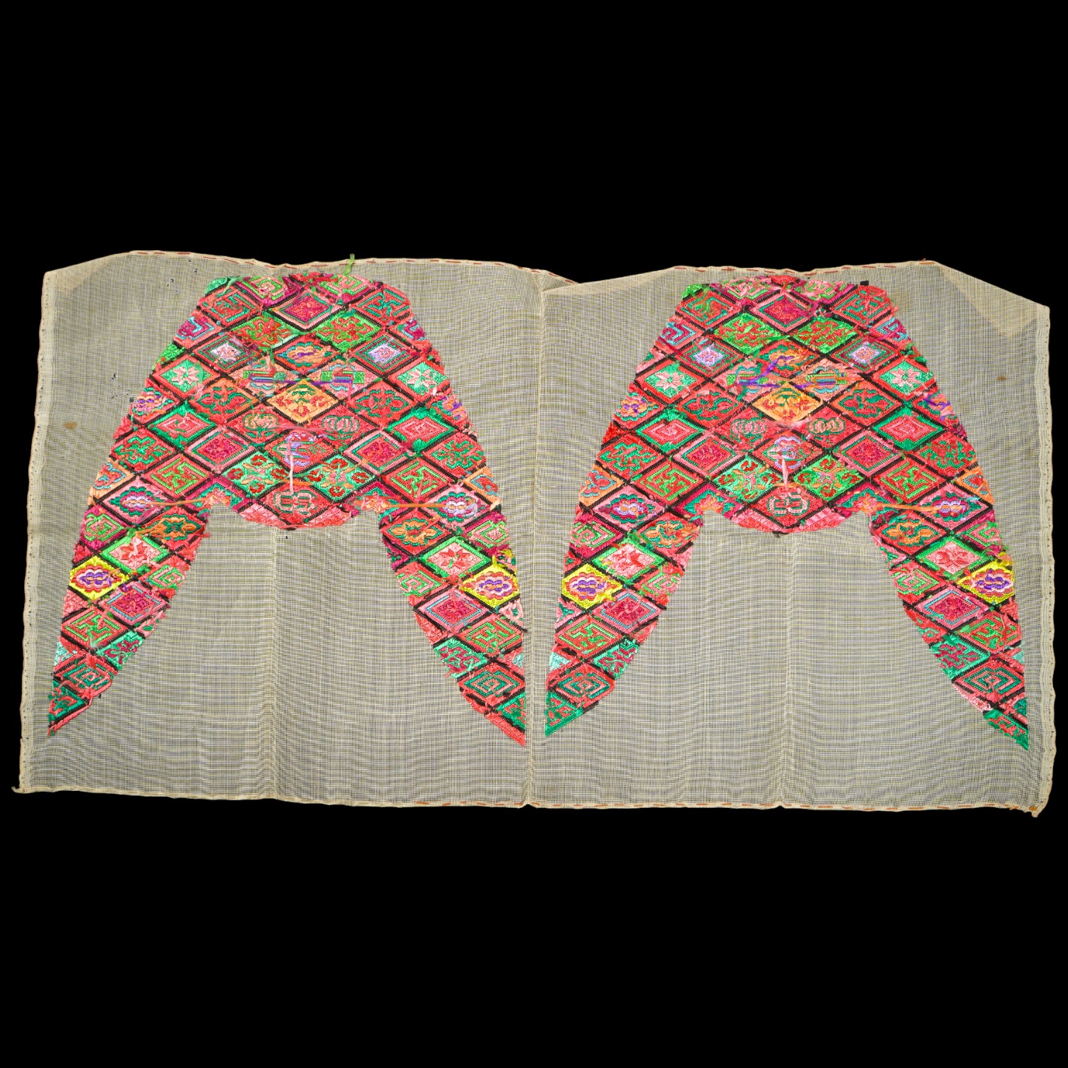 A pair of early 20th century Chinese silk polychrome finely embroidered slipper fronts, possibly from Guangxi province. Embroidered in a diamond grid, with stylistic and symbolic motifs. 21.5cm top to base. Condition - u